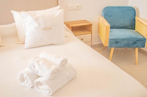 Vista de parte de la cama de matrimonio con la mesita de noche y la silla